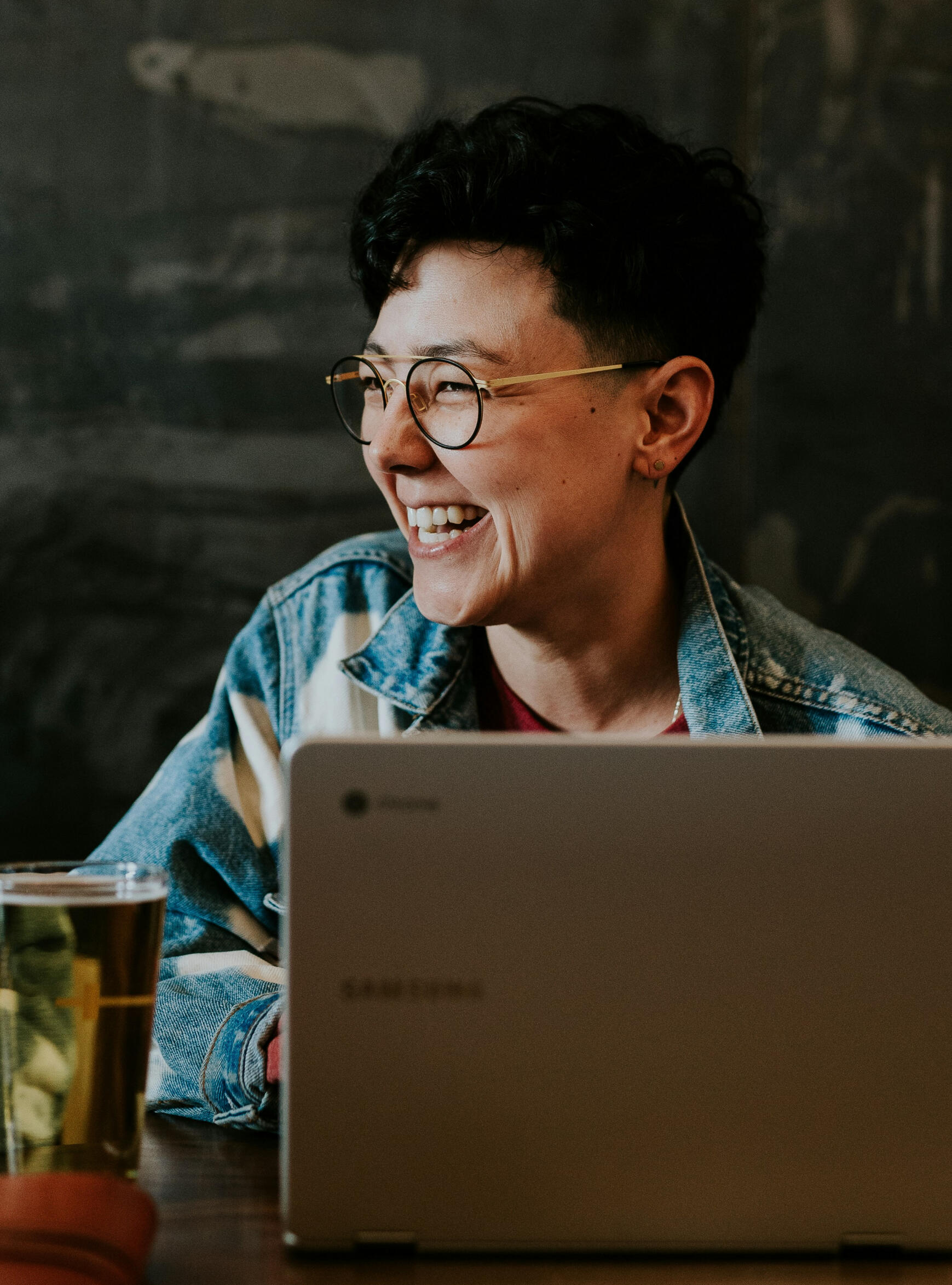 Image of a woman working at a laptop looking off to the side and laughing